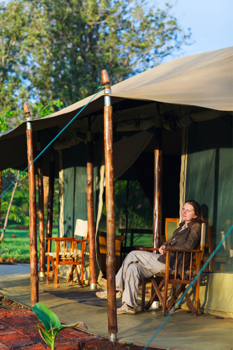 A woman sits outside a safari tent in Africa.