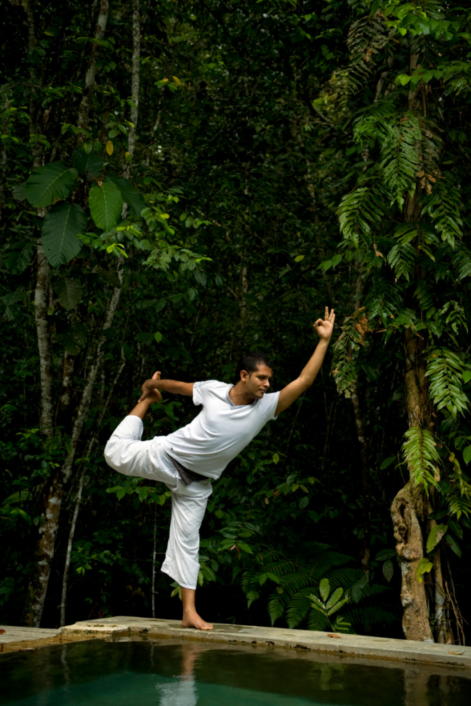 A man practices yoga in a rainforest.